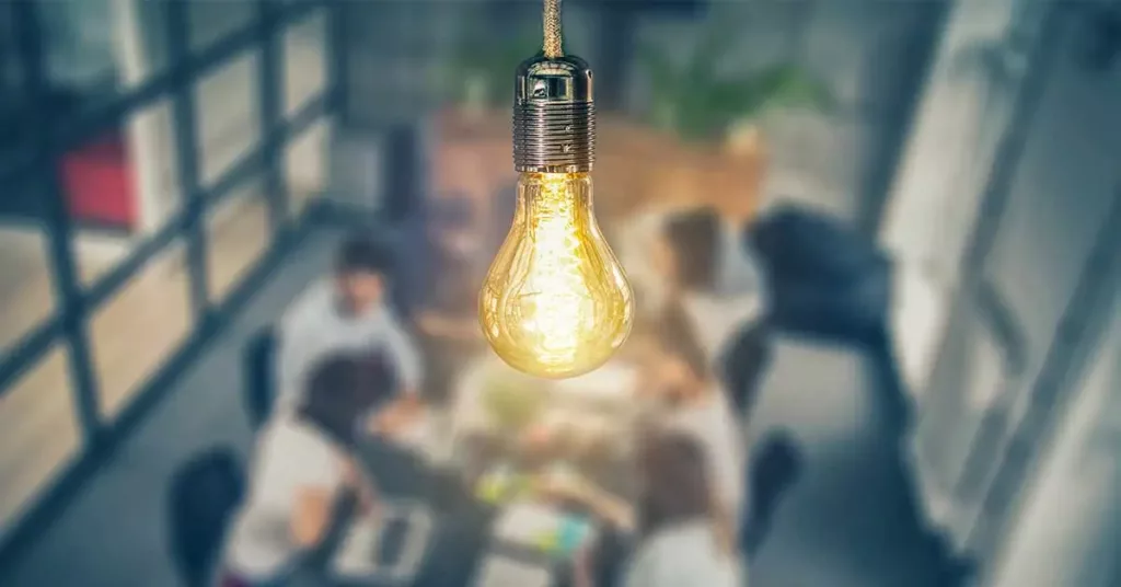 a lighbulb hanging over a team collaborating